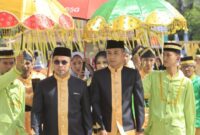 Bupati Dr. Sirajudin Lasena bersama Wakil Bupati Mohamad Aditya Pontoh disambut dengan payung adat kebesaran saat menerima gelar adat