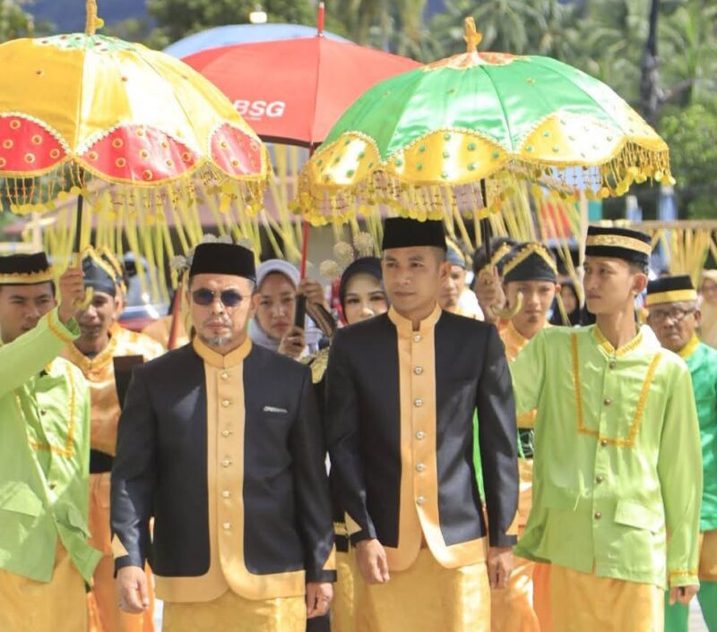 Bupati Dr. Sirajudin Lasena bersama Wakil Bupati Mohamad Aditya Pontoh disambut dengan payung adat kebesaran saat menerima gelar adat