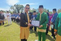 Bupati Dr. Sirajudin Lasena saat menyerahkan Piagam Penghargaan pada Kepala Dinas Nakertrans Bolmut Abdul Muis Suratinoyo