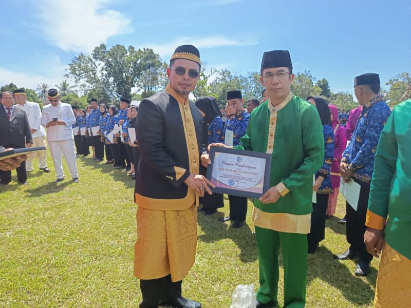 Bupati Dr. Sirajudin Lasena saat menyerahkan Piagam Penghargaan pada Kepala Dinas Nakertrans Bolmut Abdul Muis Suratinoyo