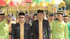Bupati Dr. Sirajudin Lasena bersama Wakil Bupati Mohamad Aditya Pontoh disambut dengan payung adat kebesaran saat menerima gelar adat