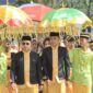 Bupati Dr. Sirajudin Lasena bersama Wakil Bupati Mohamad Aditya Pontoh disambut dengan payung adat kebesaran saat menerima gelar adat