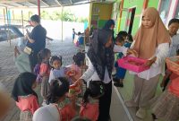 Bunda TK PAUD Budi Mania Boroko, saat membagikan makanan bergizi jenis buah-buahan pada anak didik usia dini
