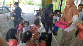 Bunda TK PAUD Budi Mania Boroko, saat membagikan makanan bergizi jenis buah-buahan pada anak didik usia dini