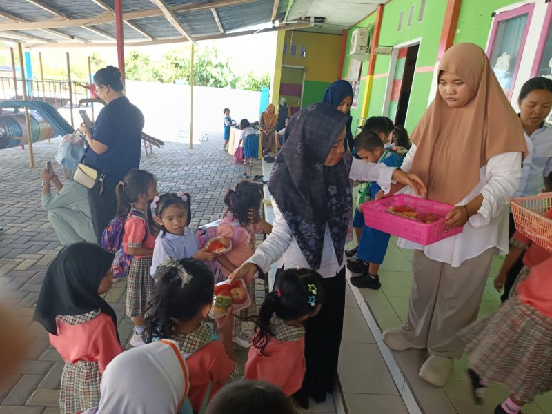 Bunda TK PAUD Budi Mania Boroko, saat membagikan makanan bergizi jenis buah-buahan pada anak didik usia dini