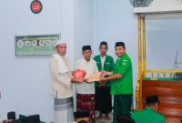 Ketua GP Ansor Boltara, Agung Aditya Saenong menyerahkan Al-Quran di Momen safari ramadhan dan diterima langsung oleh Imam Masjid Al-Ikhsan Desa Binjeita
