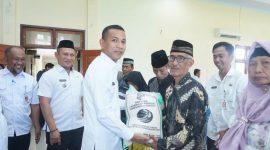 Wakil Bupati Boltara, Moh. Aditya Pontoh menyerahkan bantuan beras cadangan pangan kepada masyarakat penerima manfaat